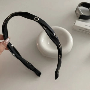 Chic black faux leather headband with silver eyelets for a stylish punk look