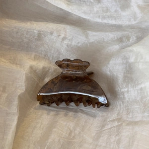 Vue détaillée d'une pince à cheveux en acétate écaille de tortue sur tissu beige