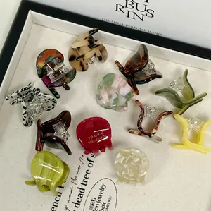 Assorted acetate resin round hair claws in tortoiseshell and cow patterns on a tray