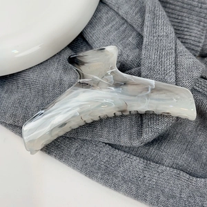 Détail d'une grande pince à cheveux marbrée style encre sur fond en tissu gris