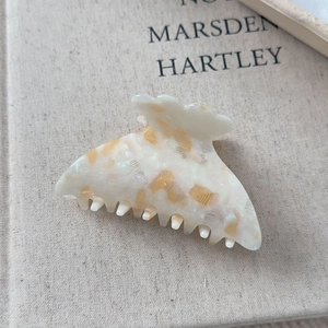 Détail macro d'une pince à cheveux en acétate crème brillant aux reflets orangés