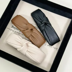 Three-color knotted faux leather hair clips set in cream, caramel, and black finishes