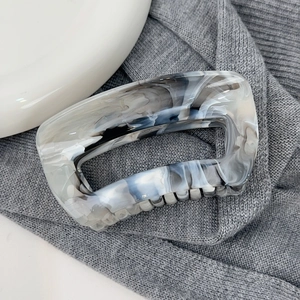 Détail d'une grande pince à cheveux avec motif marbré noir et blanc en résine polie