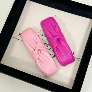 Elegant knotted PU leather hair clips in pink and rose red set on jewelry tray