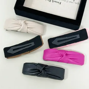 Knotted PU leather hair clip set in cream, rose, and black with metallic clip backings