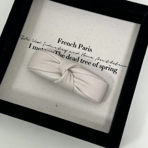 Detail of cream PU leather knotted hair clip with elegant textured finish and bow design