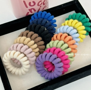 Set of 14 colorful knitted spiral phone wire hair ties in various candy colors on a black tray