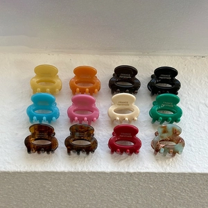 12-piece set of oval hollow acetate hair claws in various cream and pastel colors