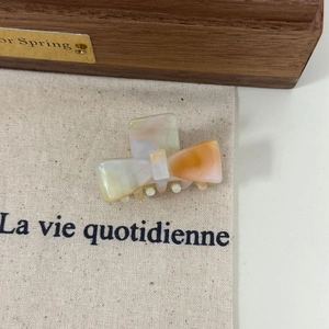 Detail of a small acetate hair claw with orange and white marble pattern for women