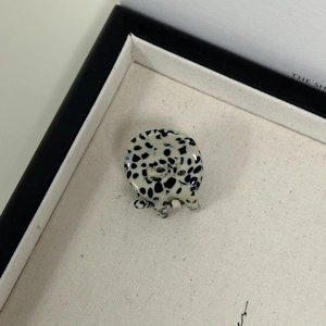 Detail of a mini round hair claw clip featuring black and white Dalmatian spot pattern