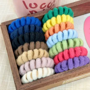 Detailed view of colorful knitted telephone wire hair ties arranged in a wooden tray
