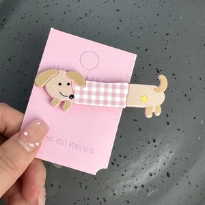 Barrette chiot teckel beige avec pull à carreaux rose et étoile jaune sur carte