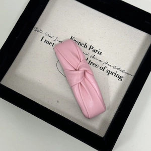 Close-up of pink PU leather knotted hair clip with elegant pleated texture on canvas