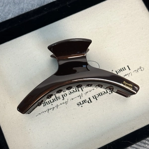 Détail d'une pince à cheveux chocolat en acétate avec inscription dorée élégante