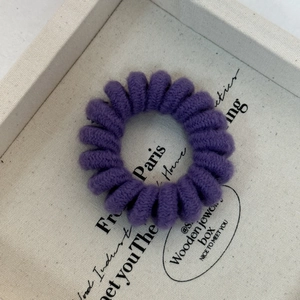Macro shot of a purple knitted spiral hair tie showing soft braided texture and elastic design