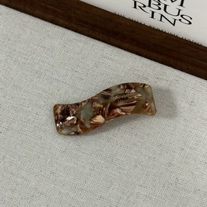 Détail d'une barrette en acétate marbré avec lettrage doré France Handmade élégant