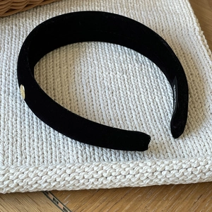 Serre-tête élégant en velours noir avec emblème doré sur fond de texture tricotée beige