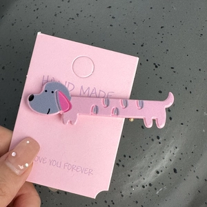 Détail d'une pince à cheveux teckel rose faite à la main sur carte cadeau décorative