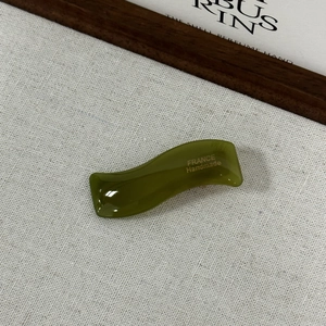 Gros plan sur une pince à cheveux ondulée en acétate vert olive gravée France Handmade