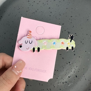 Détail d'une mignonne pince à cheveux chiot violet avec étoiles sur carte rose et plateau