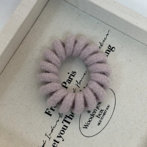 Detail of candy-colored spiral hair tie with soft dusty rose knit texture and elastic design