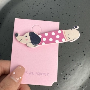 Détail d'une barrette chien teckel mignonne avec tenue à pois sur carte rose tendre