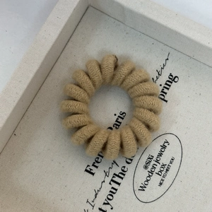 Close-up of a spiral telephone cord hair tie with a soft knit fabric in latte color