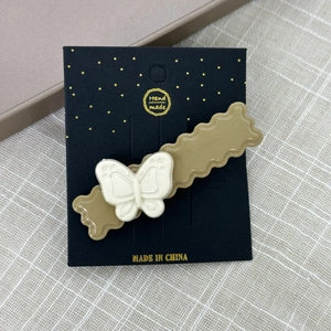 Détail de la pince à cheveux ondulée marron avec papillon blanc 3D sur carte cadeau