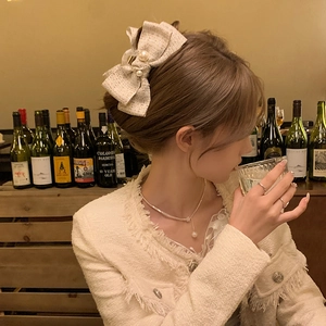 Elegant French style tweed bow hair claw clip with pearls shown on model in warm lighting