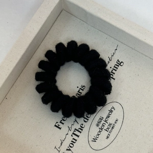 Detail of a black knit spiral telephone wire hair tie on a decorative jewelry tray