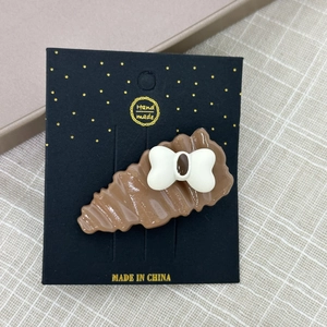 Gros plan d'une barrette à cheveux marron ondulée avec un petit nœud blanc