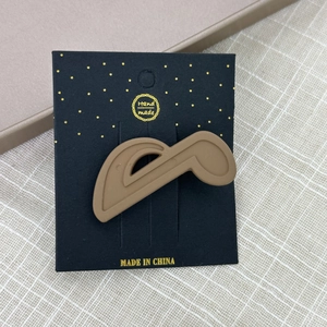 Gros plan d'une barrette à cheveux en forme de note de musique marron mat sur carte