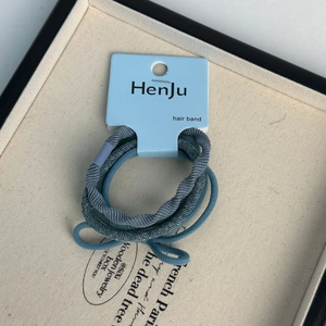 Detailed view of three blue knitted hair elastic bands on a branded product card