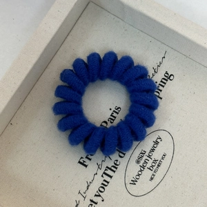 Close-up of a royal blue knit spiral hair tie displayed in a jewelry box