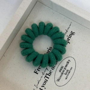 Close-up of green candy-colored spiral hair tie with a soft knitted fabric texture