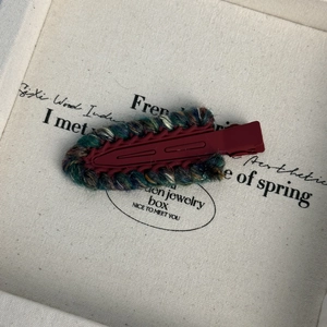 Détail de la pince à cheveux rouge mat avec bordure en laine tricotée multicolore