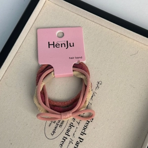 Detail of high-elasticity spiral hair ties in pink, beige and red with bow accent