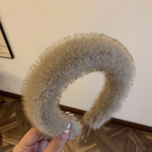 Close-up of a wide plush hairband in beige faux mink fur for women's winter headwear