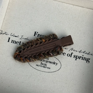 Détail macro d'une pince à cheveux rétro en laine tricotée marron et orange épaisse