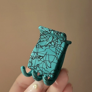 Pince à cheveux mate verte avec motifs abstraits noirs pour coiffure élégante