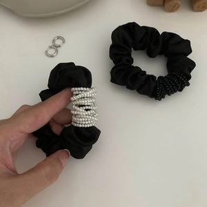 Détail de deux chouchous en satin noir avec perles blanches et petites billes noires
