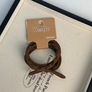 Detail of a dark brown elastic hair band with spiral texture and knot bow on a display card