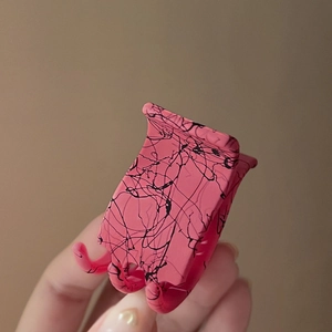 Gros plan sur la pince à cheveux rose mat avec texture mouchetée noire et dents robustes