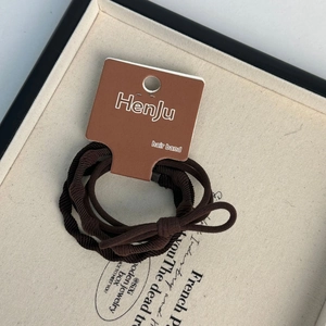 Detail view of coffee brown elastic hair bands with ribbed texture on a branded card