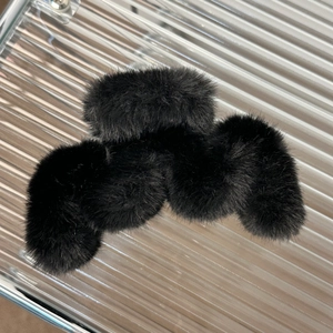 Macro shot of large black plush hair claw clip with fluffy faux fur and wave design