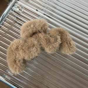 Close-up of a large brown plush wavy claw clip with soft faux fur texture for winter