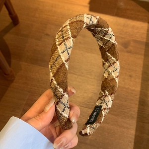 Brown plaid academic style headband with handmade label on warm wooden background