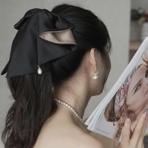 Elegant black satin bow hair claw clip with pearl drop detail shown on a model