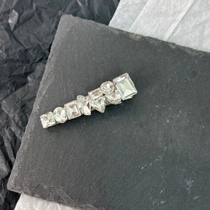 Macro shot of silver metal hair clip with geometric rhinestones on a grey slate