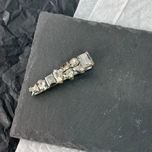 Macro detail of geometric mixed-cut crystals on a silver-tone luxury hair clip